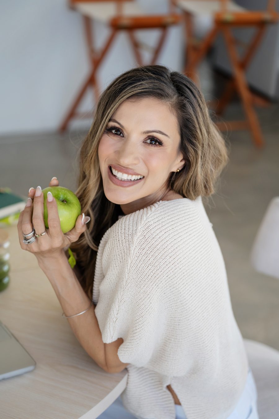 Cici holding a green apple, looking over her shoulder toward the camera