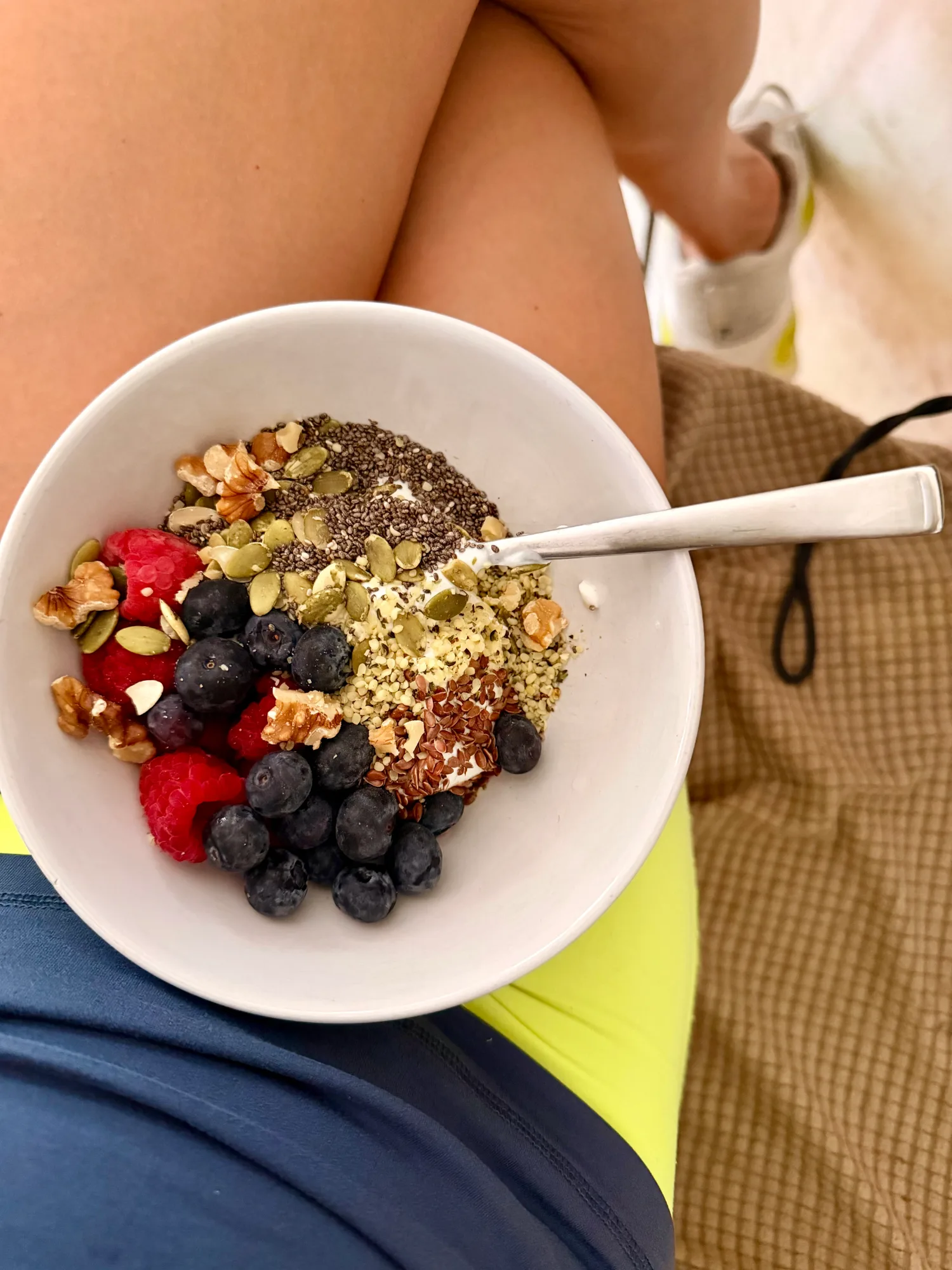 Cici McGuane holding a bowl of yogurt topped with fresh berries in her lap