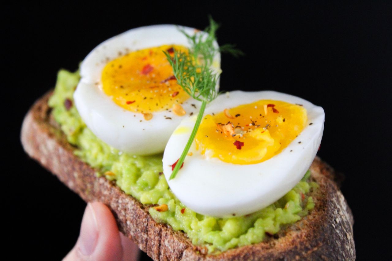 Avocado toast topped with sliced hard-boiled eggs on a plate