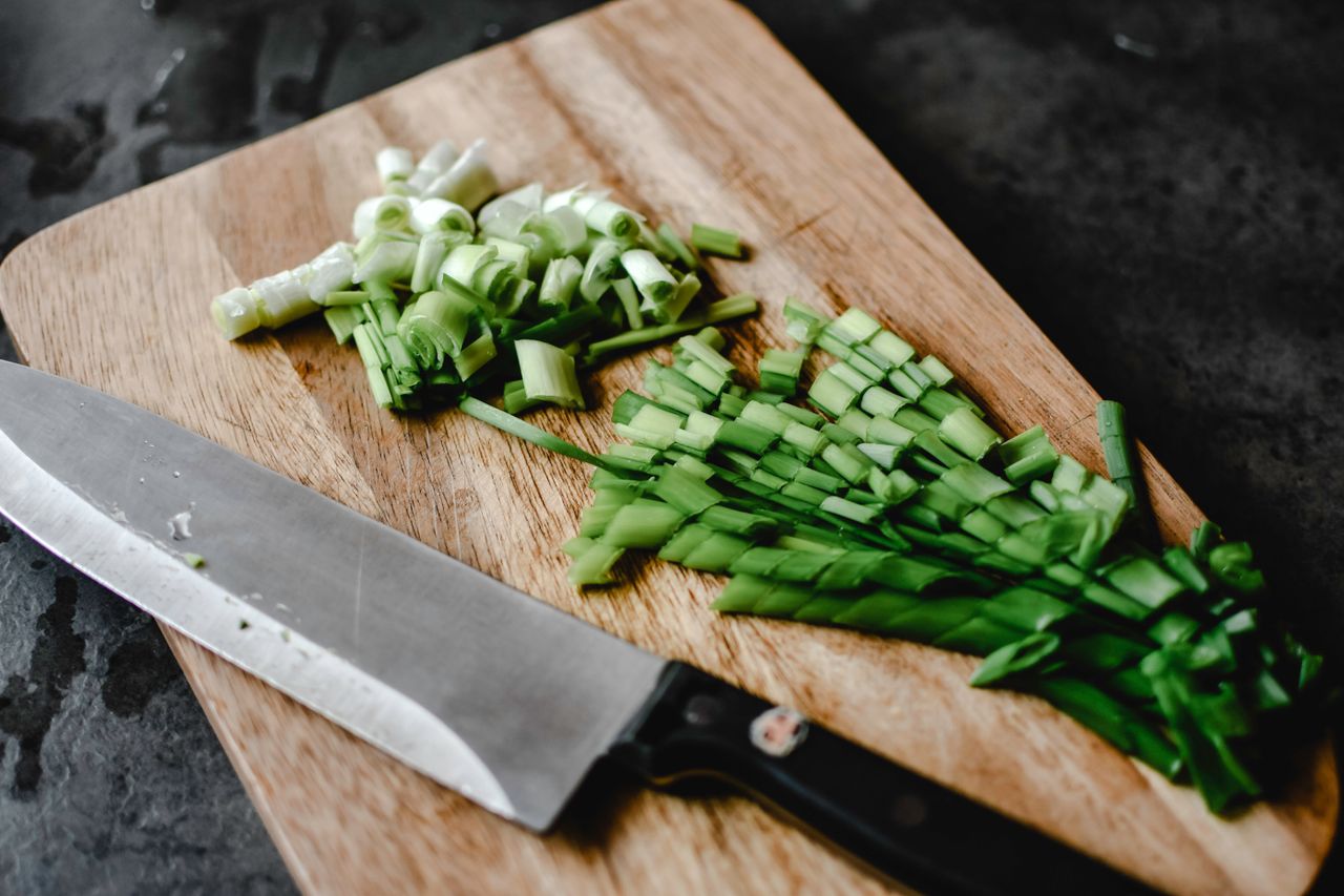 Sliced green onions arranged on a cutting board with a knife